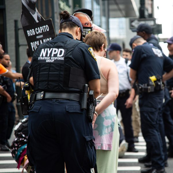 An officer binds a protester’s hands behind their back.
